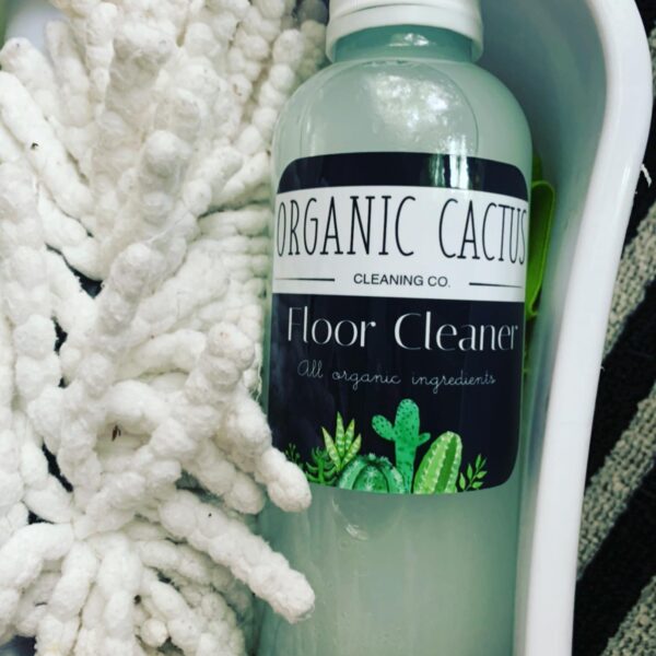 A bottle of organic cactus floor cleaner next to some white flowers.