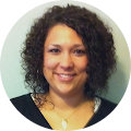 A woman with curly hair is smiling for the camera.